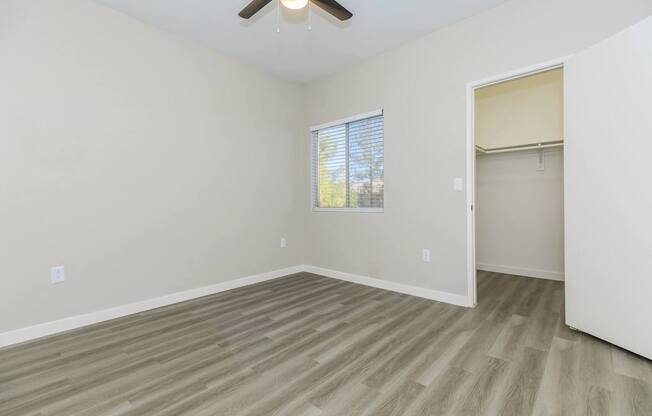 A room with a ceiling fan and a window with blinds.