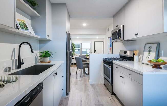 A modern kitchen with white cabinets and a wooden floor.