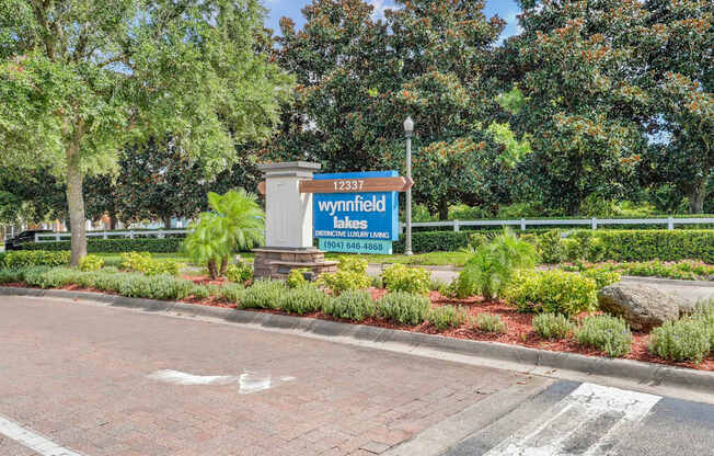 A sign for Wynnfield Lakes is displayed in front of a landscaped area at Wynnfield Lakes Apartments in Jacksonville, FL