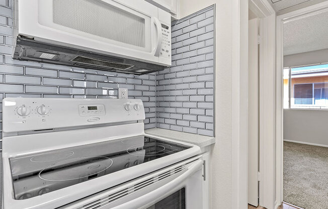 White tiled kitchen with stainless steel oven and microwave.