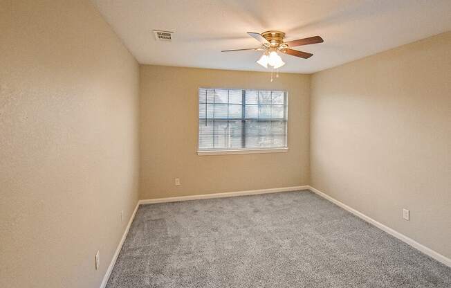 A room with a ceiling fan and a window.