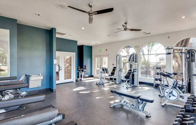 A spacious gym with a variety of equipment and a person working out in the background.