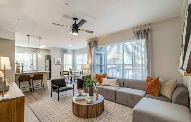 A living room with a grey couch, a wooden coffee table, and a ceiling fan.