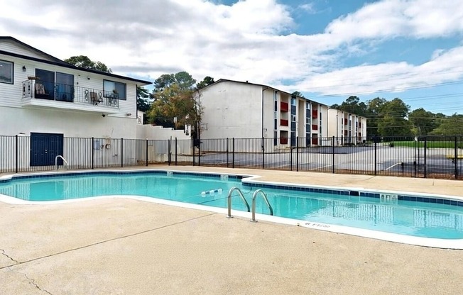 A swimming pool in a residential area with apartment buildings in the background.