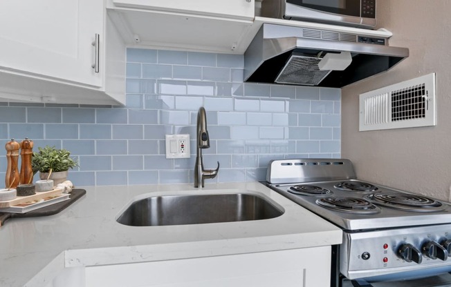 a kitchen with white cabinets and a stainless steel sink