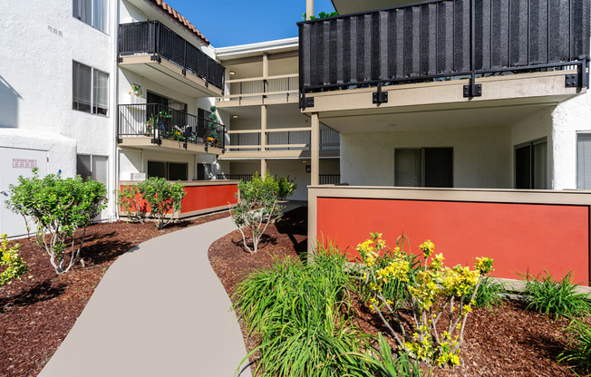 an exterior view of an apartment building with a walkway and plants