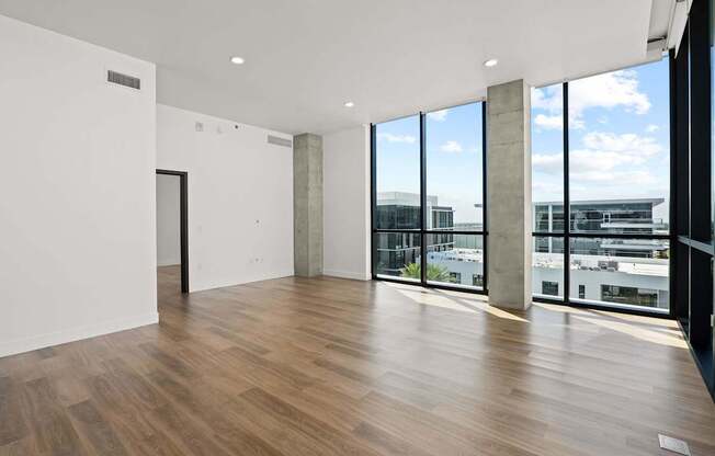 A room with wooden floors and a view of the city through large windows.