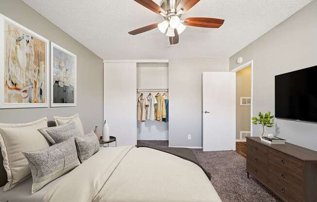 A bedroom with a large bed, a ceiling fan, and a television.