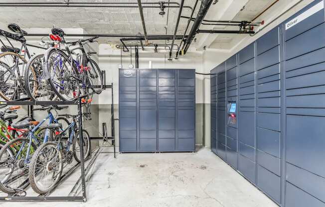 A bike rack with several bicycles is in front of a wall of blue lockers.