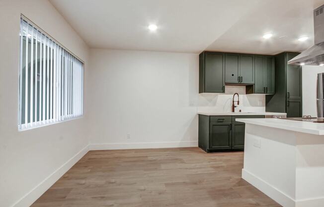 an empty kitchen and living room with white walls and black cabinets