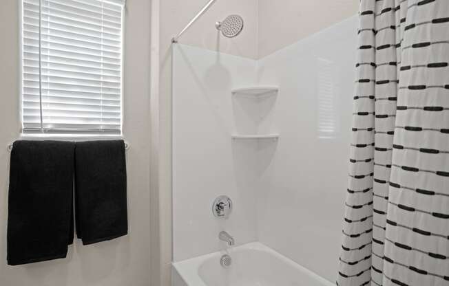 a white bathroom with a shower and black towels