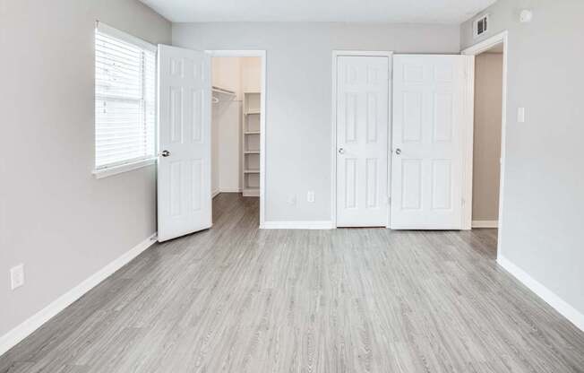 A room with white doors and wooden flooring.