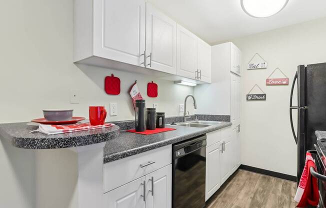 A kitchen with white cabinets and a black refrigerator.
