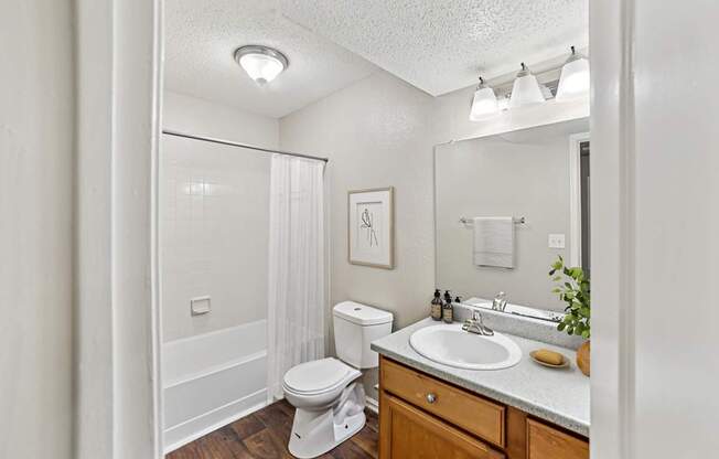 A white bathroom with a toilet, sink, and mirror.