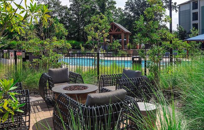 a patio with chairs and a table near a pool