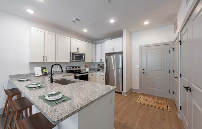 A kitchen with a granite countertop and a stainless steel refrigerator.