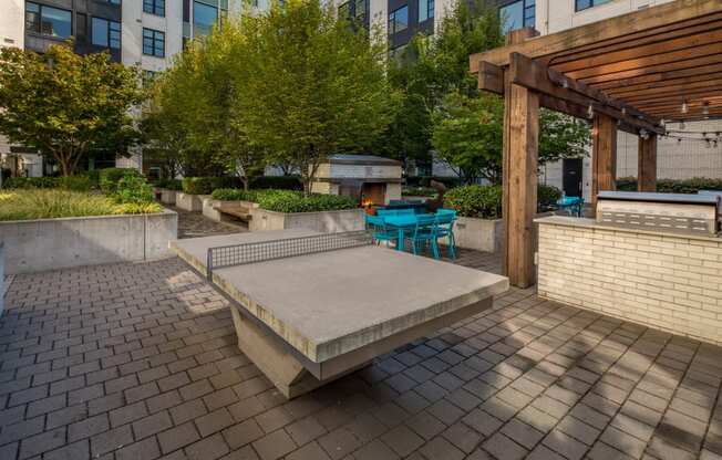 an outdoor seating area with a concrete ping pong table and a wooden pergola at The Parker, Oregon, 97209