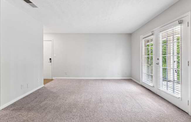 A room with a carpeted floor and a sliding glass door.
