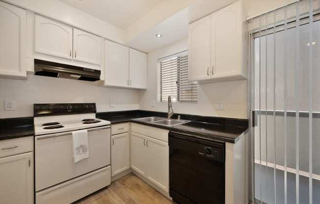 a kitchen with white cabinets and black counter tops and white appliances