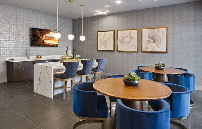 a dining room with blue chairs and tables and a kitchen at Aura Vegas Apartments, Las Vegas, NV 89103
