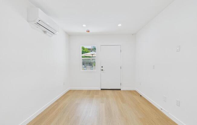 A room with a white door and a window showing greenery outside.