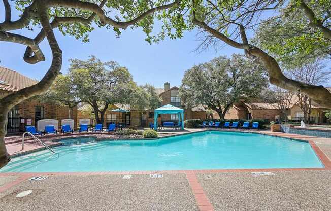 A swimming pool surrounded by trees and chairs.