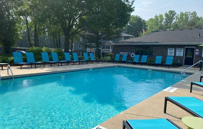 A pool with blue chairs and a building in the background.