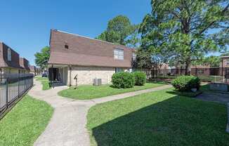 A building with a brown roof is surrounded by a green lawn and trees.