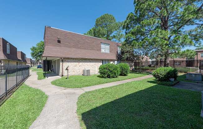 A building with a brown roof is surrounded by a green lawn and trees.
