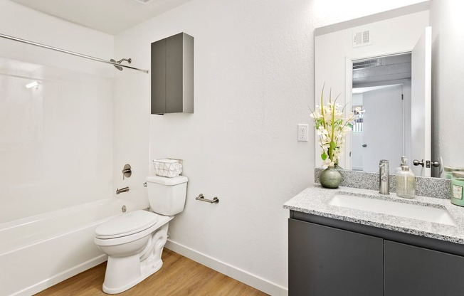 A white toilet sits in a bathroom next to a sink.