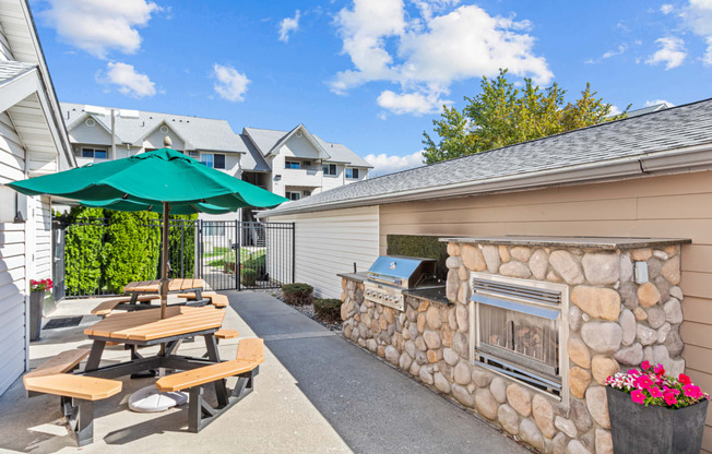 an outdoor patio with picnic tables and a stone fireplace