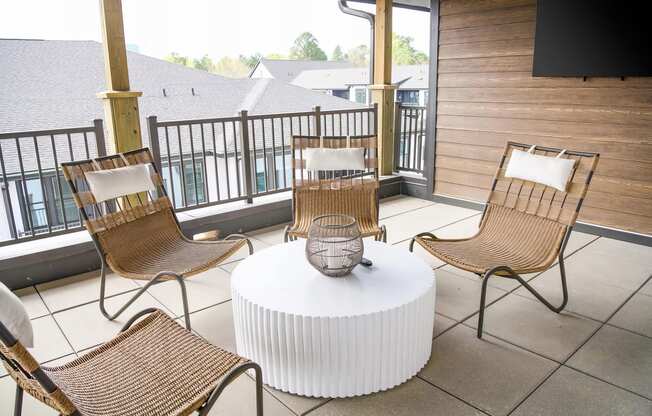 Cozy balcony with wicker style chairs and large flatscreen television at Novel Cary