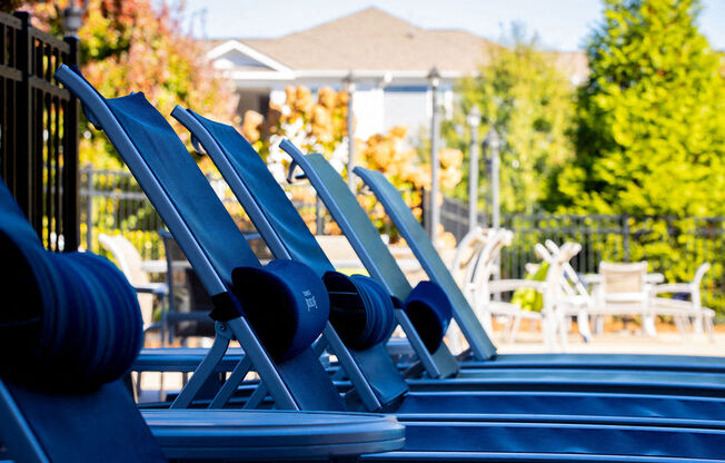 a row of blue deck chairs at a pool