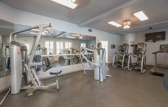 A gym with a variety of equipment including a treadmill, a stationary bike, and a weight bench at Autumn Oaks Apartments, Roseville, CA, 95678
