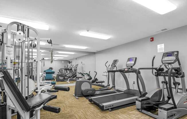 a gym with various cardio equipment and weights on the floor