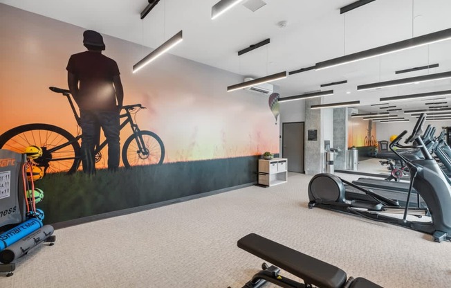 A gym with a wall mural of a person on a bike.