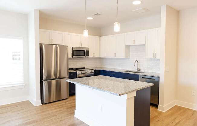 A kitchen with a refrigerator, microwave, oven, and sink.