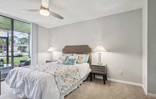 A bedroom with a bed, nightstand, and a ceiling fan.