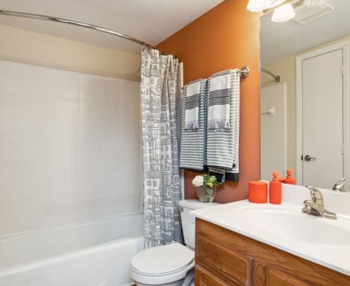 a bathroom with orange walls and a white bathtub  at Lake Johnson Mews, Raleigh