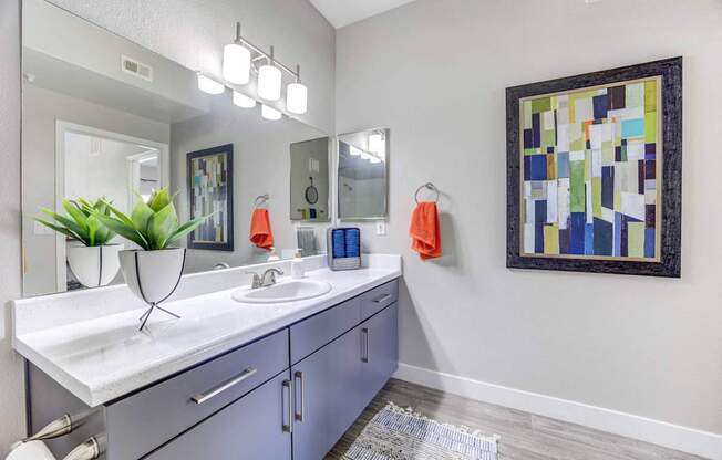 A bathroom with a white counter top and a large mirror.