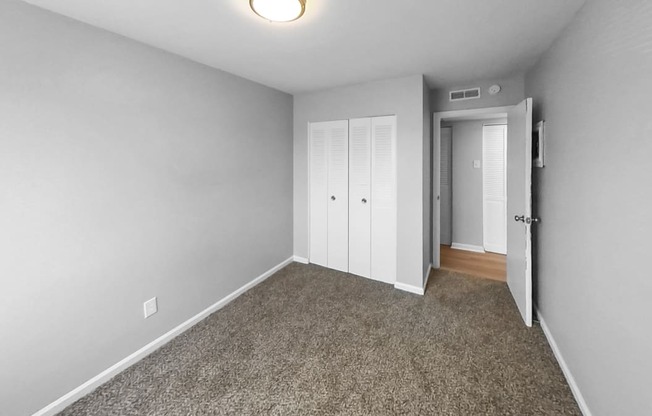 a bedroom with a carpeted floor and a door to a closet