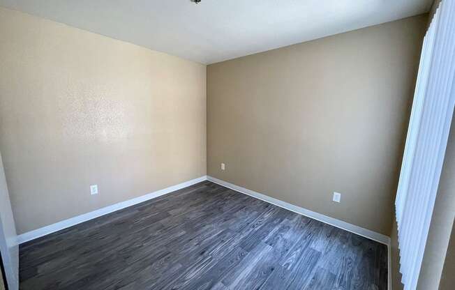 a bedroom with hardwood floors and beige walls