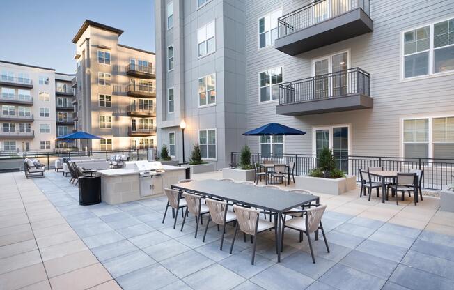 An open-air courtyard at Modera Liberty Row features outdoor dining, grilling stations, and lounge seating designed for everyday gatherings in the heart of Charlotte.