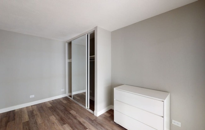 a bedroom with grey walls and hardwood floors