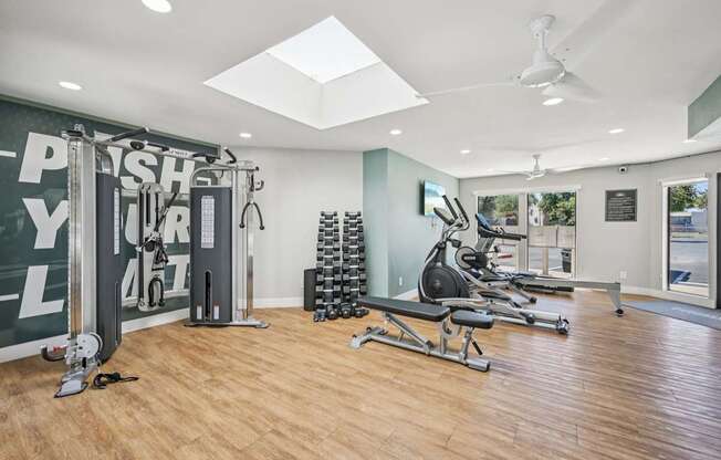 A gym with a variety of equipment including a squat rack, a leg press machine, and a rowing machine.