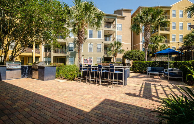 a patio with tables and chairs in front of an apartment building