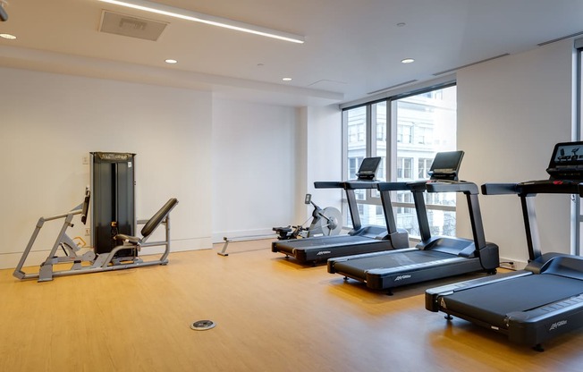 A gym with treadmills, a stationary bike, and a rowing machine.