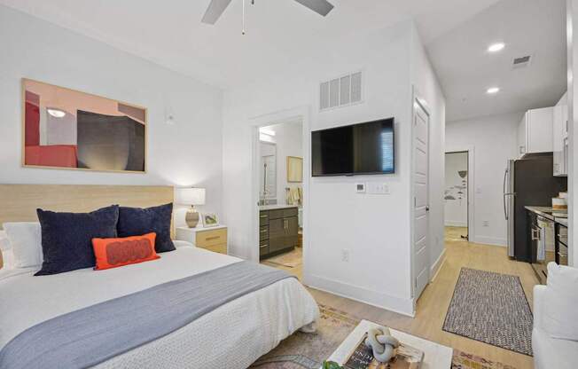 a bedroom with a bed and a tv in a white room at Link Apartments® Calyx, Chapel Hill, NC 27517