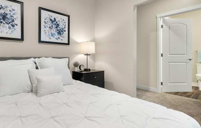 a bedroom with white bedding and two framed pictures on the wall