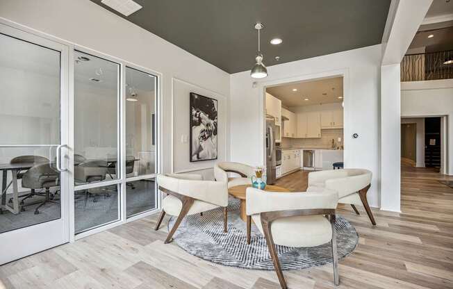 A modern dining room with a glass door leading to a kitchen.